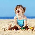 Девочка сидит на песке пляже