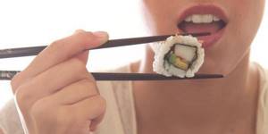 Девушка ест суши