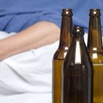 Мужчина лежит на кровати с бутылкой в руке