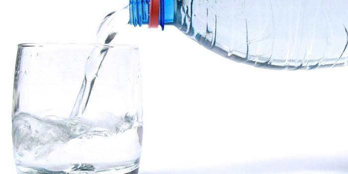 Воду наливают из бутылки в стакан